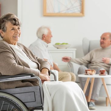 An elderly woman in a wheel chair socializing with other people