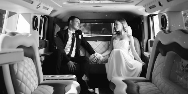 A wedded couple riding in a Stretch Limousine.