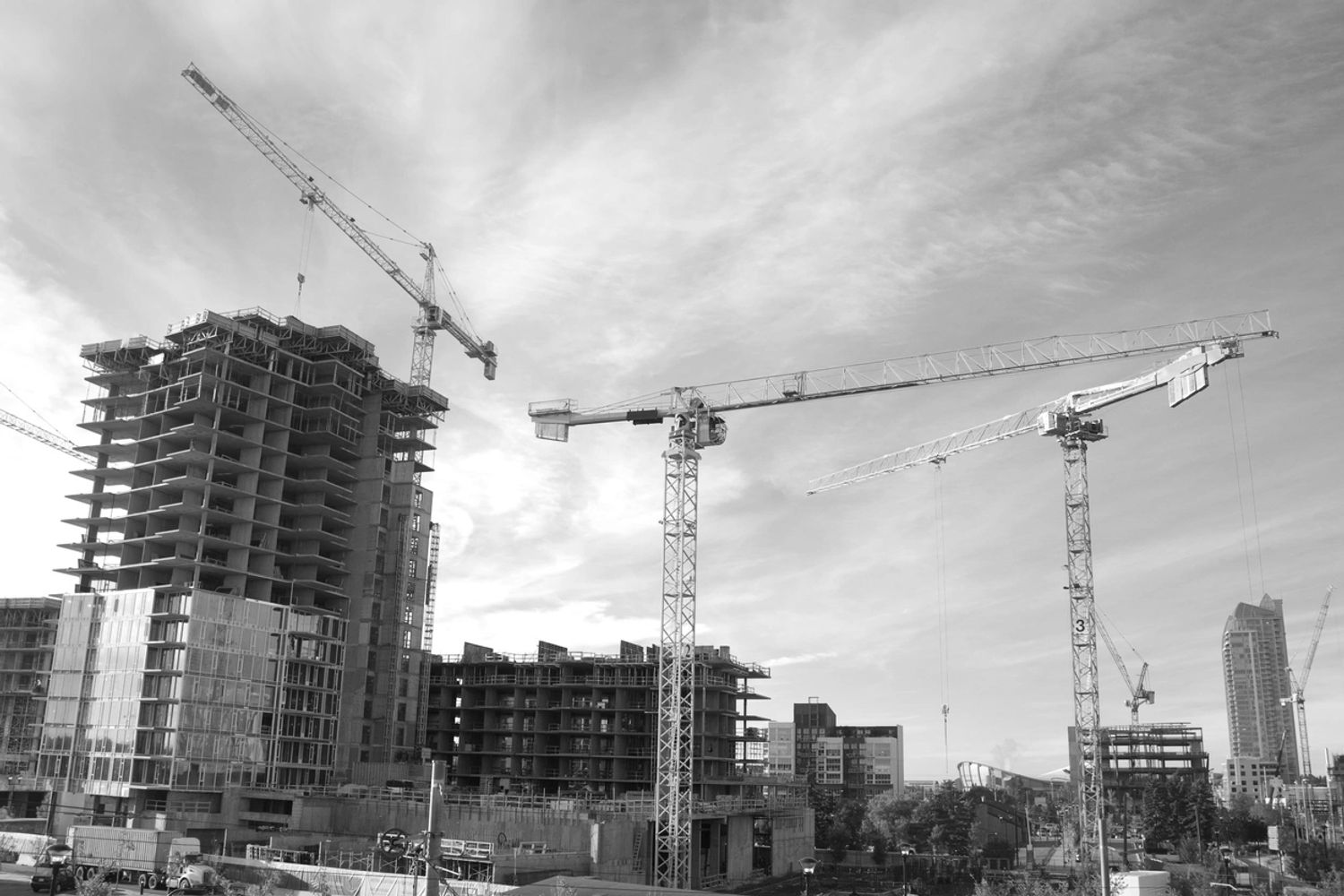 Construction site with cranes and partially built high-rise buildings under a clear sky.
