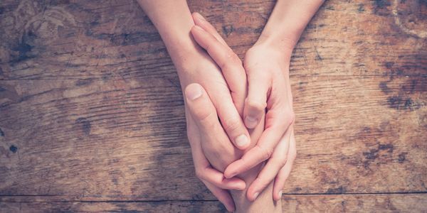 Two people holding hands on a wooden table.