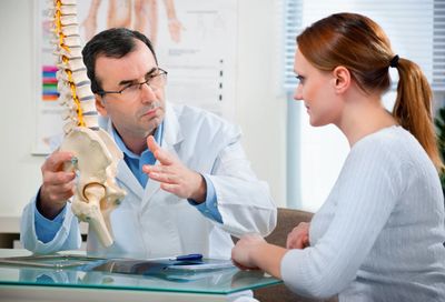 Doctor explaining spine anatomy to patient using a model.