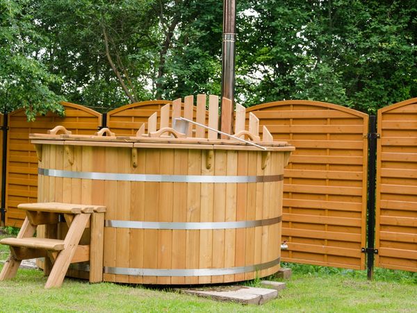 Wooden outdoor hot tub with a small staircase in a garden.