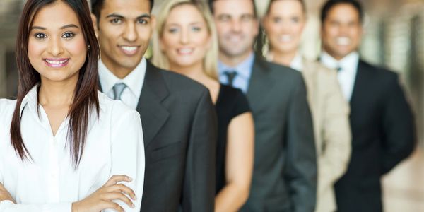 Six smiling females and males of varying ages in business suits