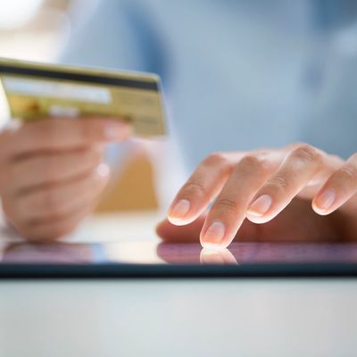 Person using a tablet and holding a credit card for online payment.
