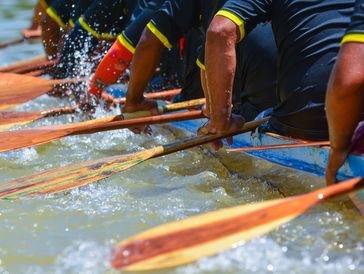 Rowers paddling intensely in a boat race, splashing water.