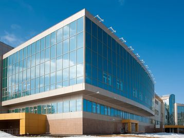Modern glass and concrete office building under a clear blue sky.