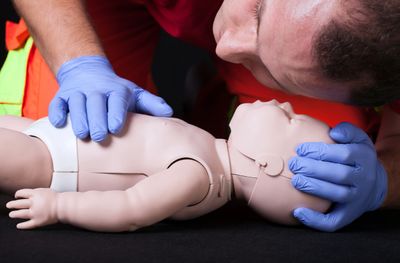 Person practicing CPR on an infant mannequin.