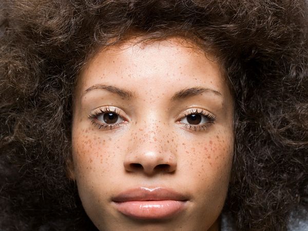Close up of beautiful mixed-raced woman, with natural skin, no makeup and freckles.
