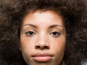 Close-up of a young woman with curly hair and freckles.