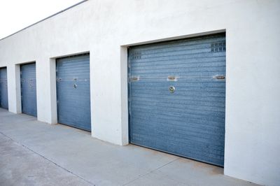 Row of closed blue garage doors on a white building.