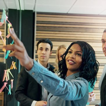 Employees standing and pointing at sticky notes in a meeting