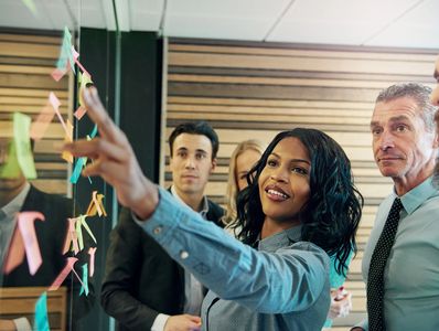 Diverse group of businesspeople at board with post-it notes.