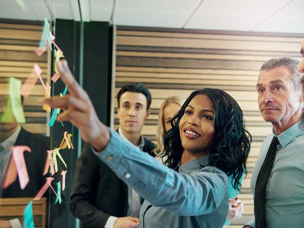 Consultants looking at some sticky notes on a glass wall