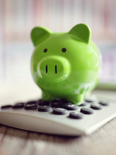 Green piggy bank on a calculator, symbolizing savings and financial planning.