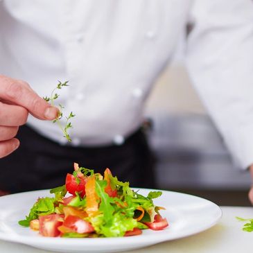 a chef carefully dressing a salad 