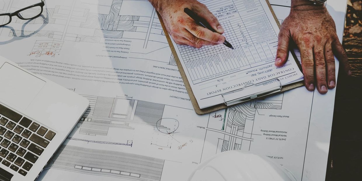 Person filling out construction report on an architectural blueprint.