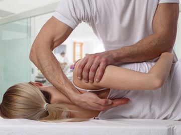A chiropractor performing a manual therapy to the shoulder. 