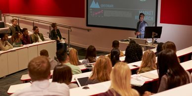 A speaker presents to an engaged audience in a modern lecture hall.