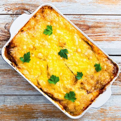 Baked cheesy casserole garnished with parsley in a white dish.