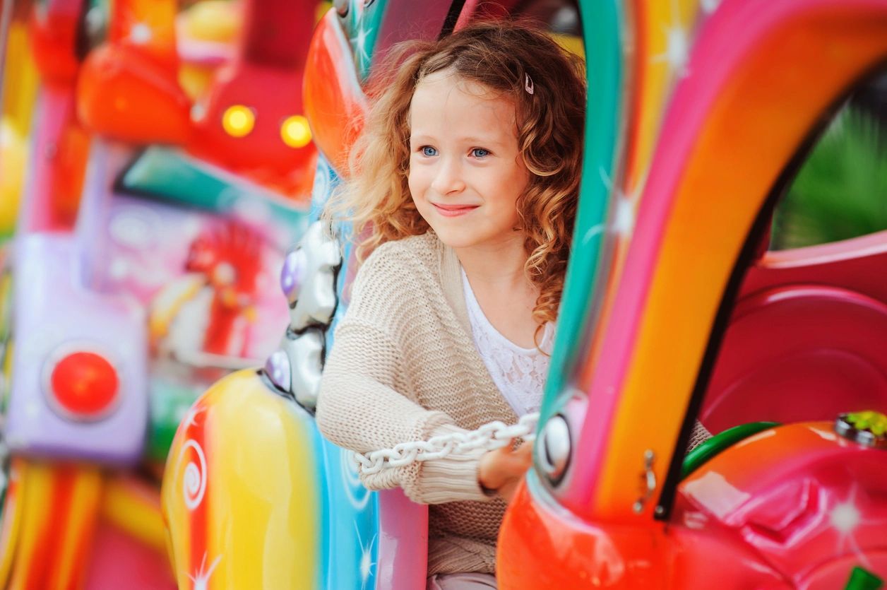 Smiling girl enjoying a colorful amusement ride.
