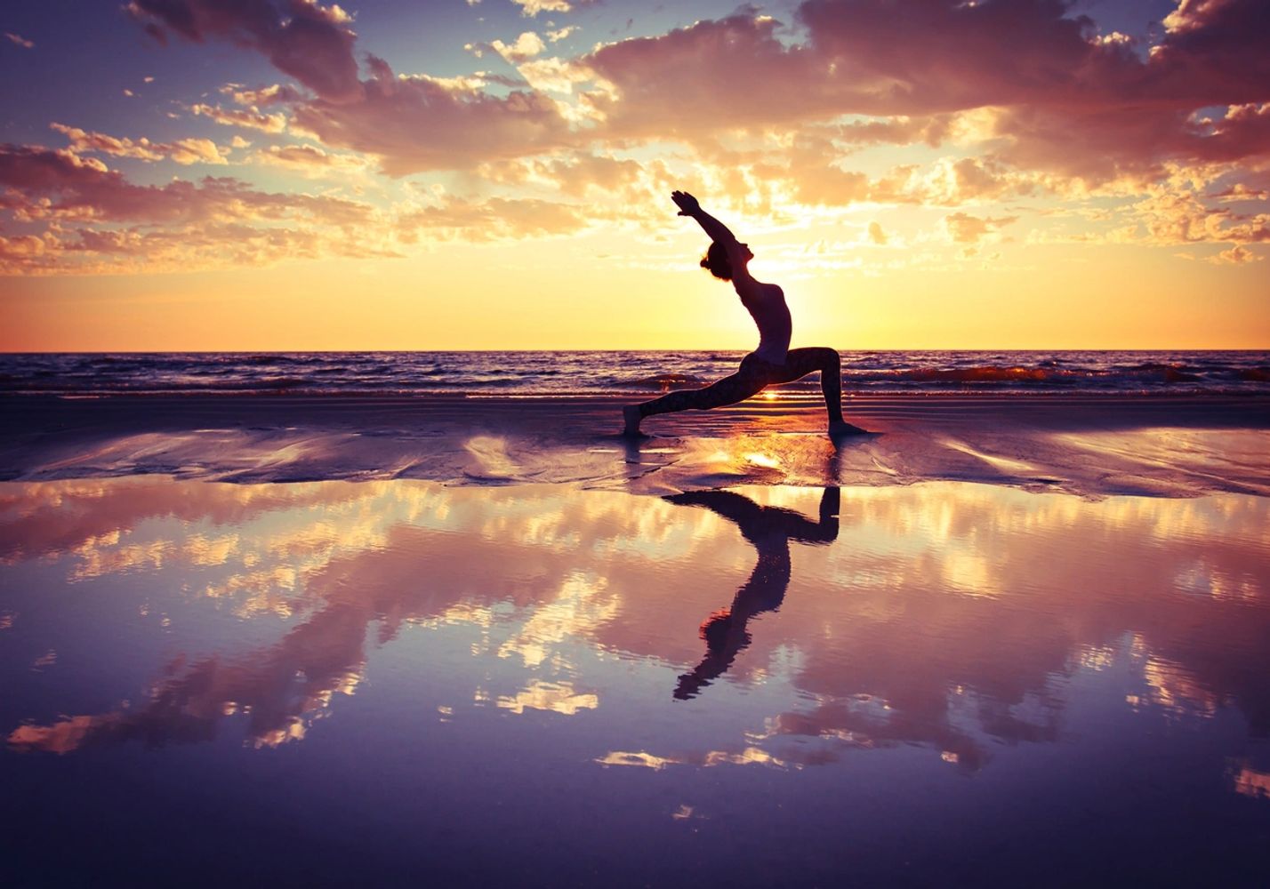 Person stretching on beach during sunset