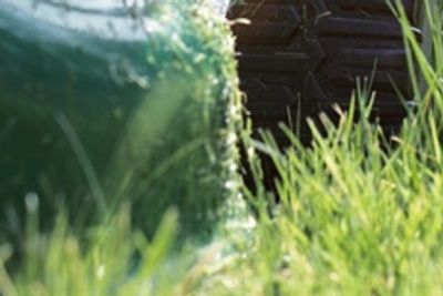 A professional performing tractor mowing on a large green field.
