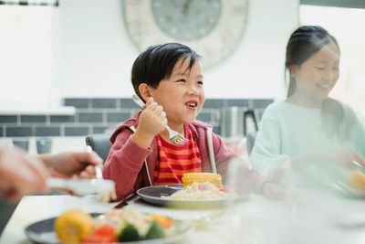 A joyful child enjoying a meal with family at the dining table.