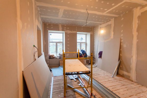 Room under renovation with drywall and construction materials scattered around.