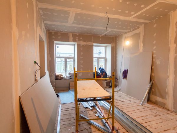 Room under construction with drywall and scaffolding inside.