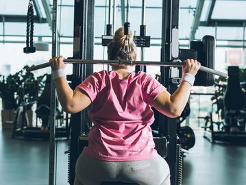 Woman doing a lat pulldown exercise in a gym.
