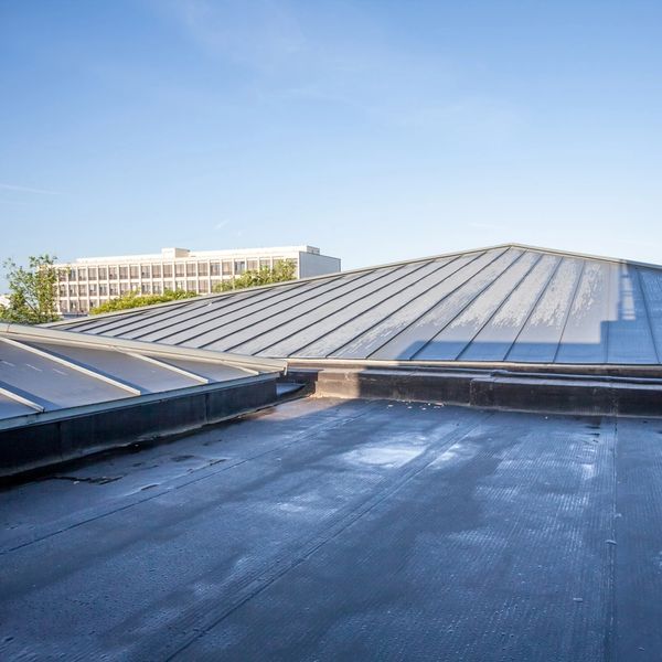 Flat rooftop with large slanted glass panels under clear sky.