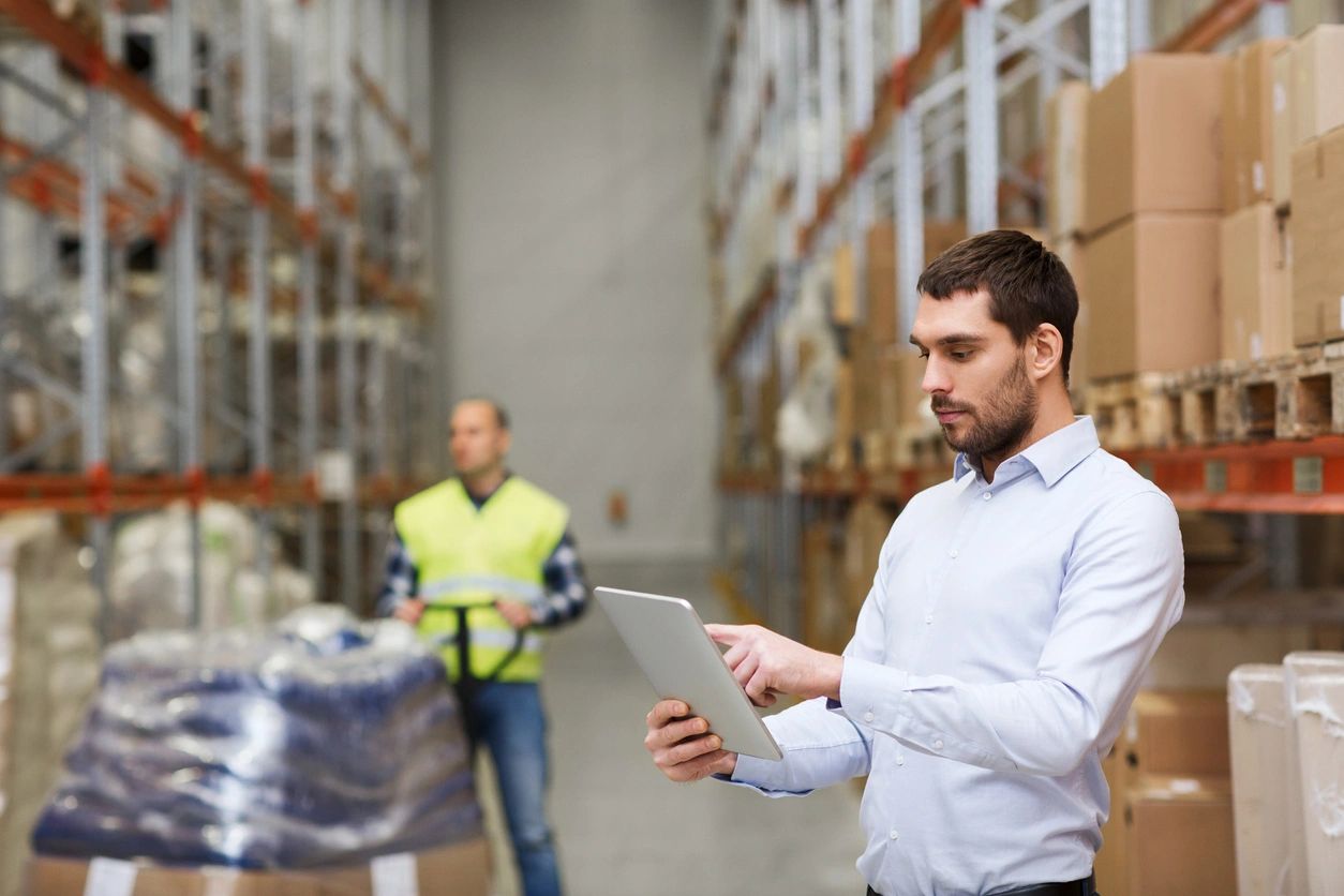 A man is using a tablet in a warehouse.