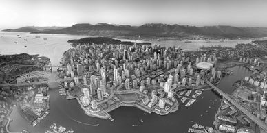 Aerial view of a coastal city with high-rise buildings and surrounding mountains at sunset.