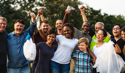 A diverse group of people smiling and celebrating outdoors.