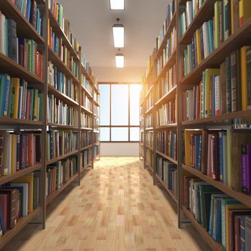 Bookstore image with isle of books on shelves with a window at the end of the row. 