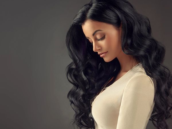 Woman with long, black hair done by a hair stylist.