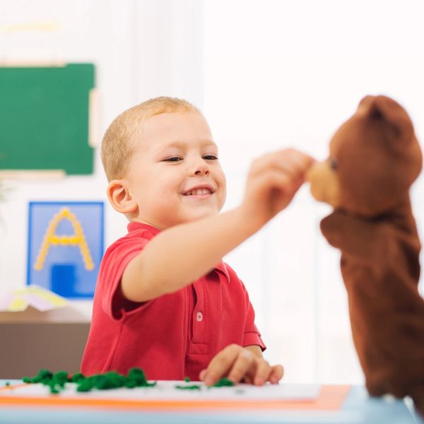 Boy playing with a teddy bear puppet.