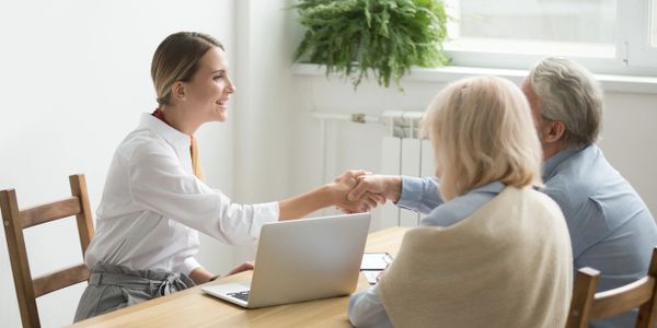 A young female and two older adults sitting around a table for a meeting.