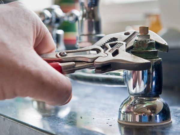 Hand using wrench to fix faucet.