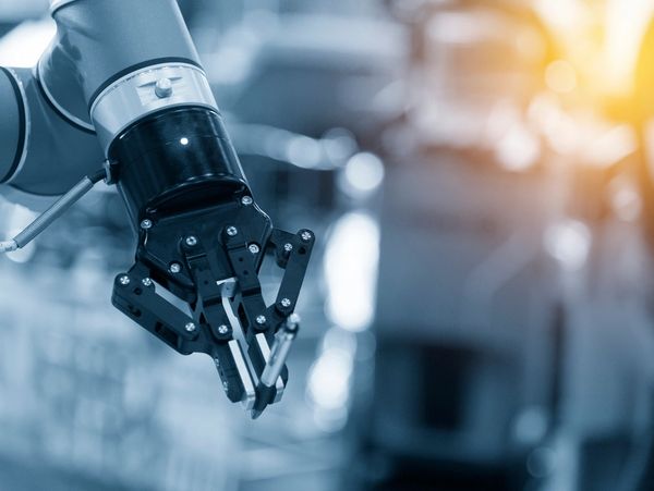 Close-up of a robotic arm with a mechanical gripper in an industrial setting.