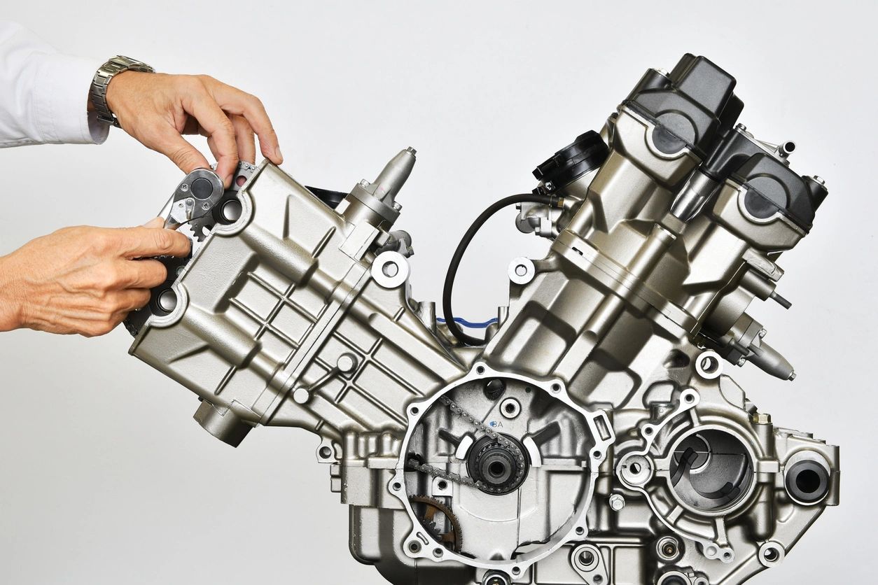 Hands adjusting a metallic engine component with a ratchet wrench.