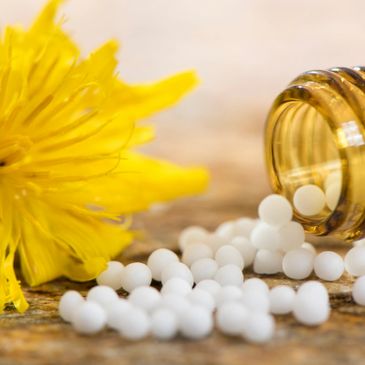 Homeopathic remedy with flower laying beside the bottle of remedies.