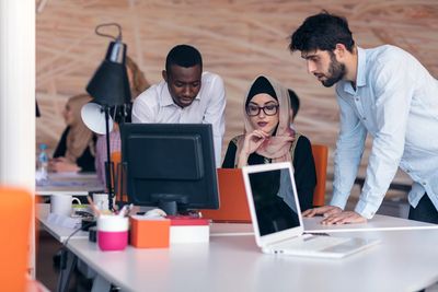 image of two men standing over a desk of a Muslim female