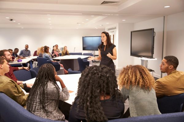 A woman giving a presentation to a diverse group in a modern meeting room.