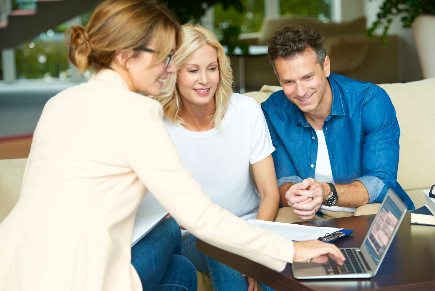 Woman typing on her laptop computer sitting around a table with a couple discussing finances.