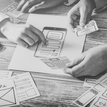 Hands working on mobile app wireframe design with paper templates.