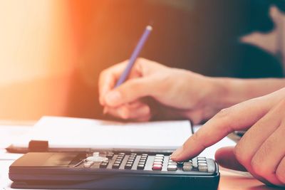 person performing calculations with a calculator and paper