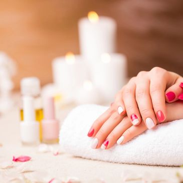 Woman's hands with colorful nail art resting on a towel in a spa setting.