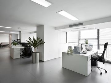 Modern office space with white desks and black chairs.