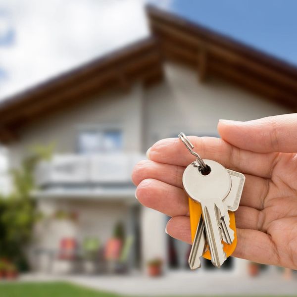 Keys in persons hand in front of a house 